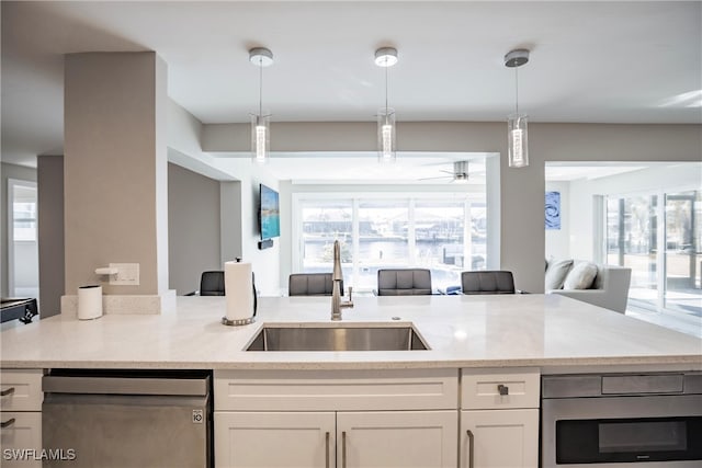 kitchen featuring pendant lighting, white cabinets, sink, appliances with stainless steel finishes, and light stone counters