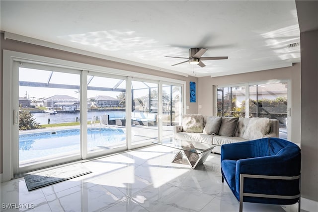 living room featuring ceiling fan, a water view, and a wealth of natural light