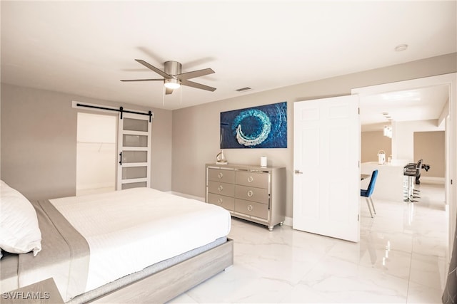 bedroom featuring a walk in closet, a barn door, a closet, and ceiling fan