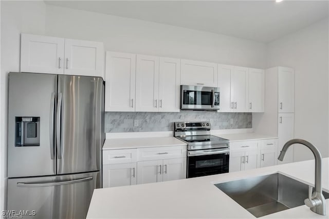 kitchen featuring white cabinets, appliances with stainless steel finishes, decorative backsplash, and sink