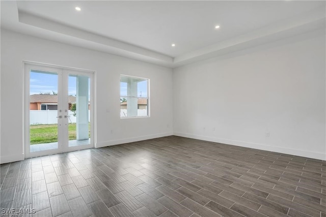 spare room with dark hardwood / wood-style floors, a tray ceiling, and french doors