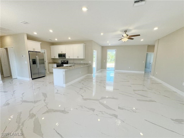 kitchen featuring kitchen peninsula, appliances with stainless steel finishes, light stone countertops, ceiling fan, and white cabinetry