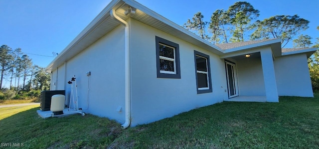 view of side of property featuring a lawn and central AC