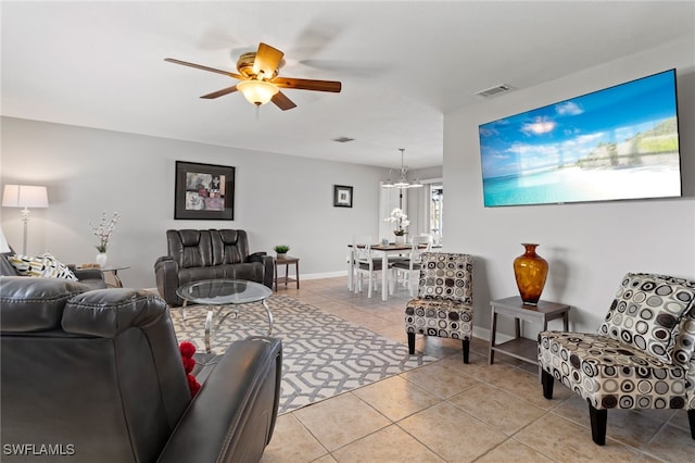 tiled living room with ceiling fan with notable chandelier