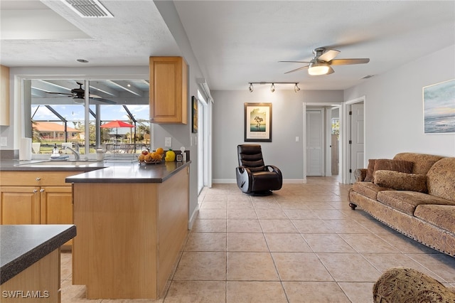 kitchen with light brown cabinetry, track lighting, a textured ceiling, sink, and light tile patterned floors