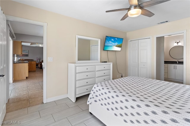 bedroom with ceiling fan, ensuite bathroom, sink, and a closet