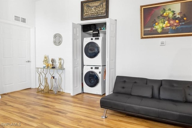 laundry area featuring hardwood / wood-style floors and stacked washer and dryer