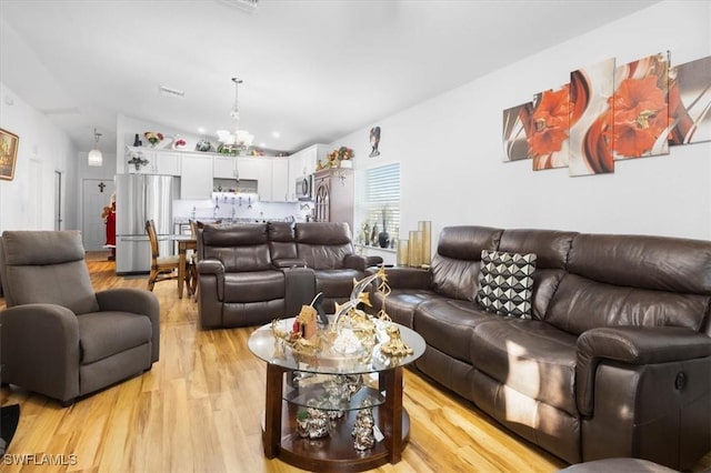 living room with a chandelier, lofted ceiling, and light wood-type flooring