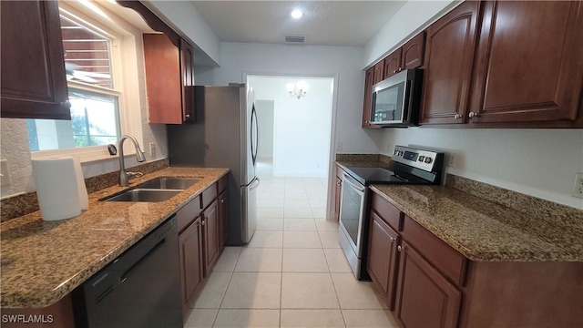 kitchen featuring stone countertops, light tile patterned floors, sink, and appliances with stainless steel finishes