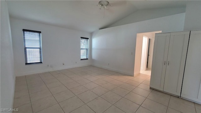 tiled spare room featuring vaulted ceiling, ceiling fan, and a healthy amount of sunlight