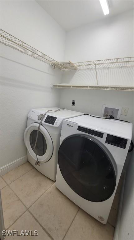 laundry area with independent washer and dryer and light tile patterned floors