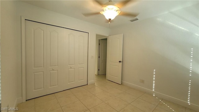 unfurnished bedroom with ceiling fan, a closet, and light tile patterned floors