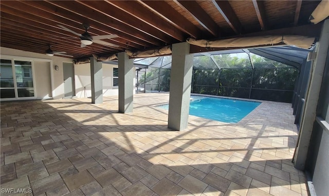 view of pool featuring glass enclosure, ceiling fan, and a patio area