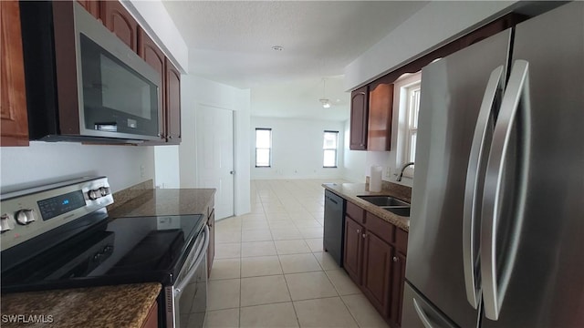 kitchen featuring sink, light tile patterned floors, stainless steel appliances, and a textured ceiling