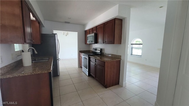 kitchen featuring light tile patterned flooring, dark stone countertops, and appliances with stainless steel finishes