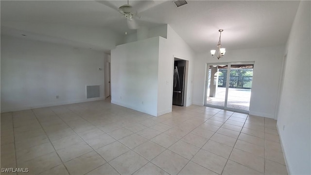 tiled empty room with ceiling fan with notable chandelier and vaulted ceiling