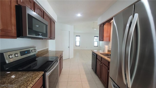 kitchen with light tile patterned floors, stainless steel appliances, and dark stone countertops