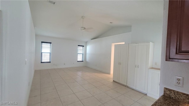 empty room featuring ceiling fan, light tile patterned floors, and vaulted ceiling