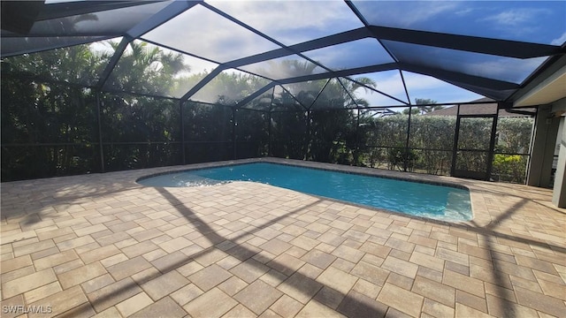 view of pool featuring glass enclosure and a patio