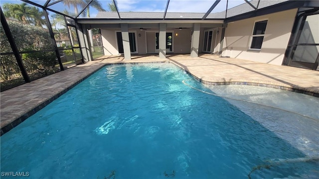 view of swimming pool with a patio, glass enclosure, and ceiling fan