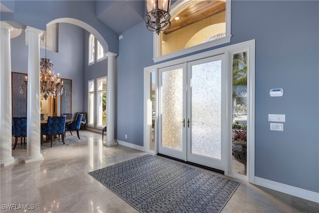 foyer featuring a chandelier, french doors, decorative columns, and a healthy amount of sunlight