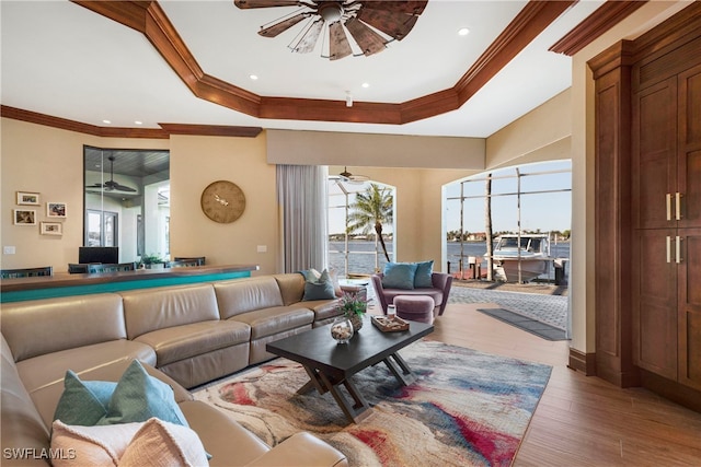 living room with ceiling fan, crown molding, a water view, and hardwood / wood-style flooring