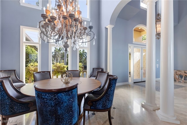 dining space featuring a towering ceiling, an inviting chandelier, and plenty of natural light