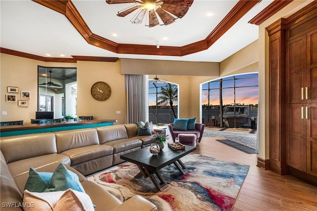 living room featuring a tray ceiling, crown molding, and hardwood / wood-style flooring