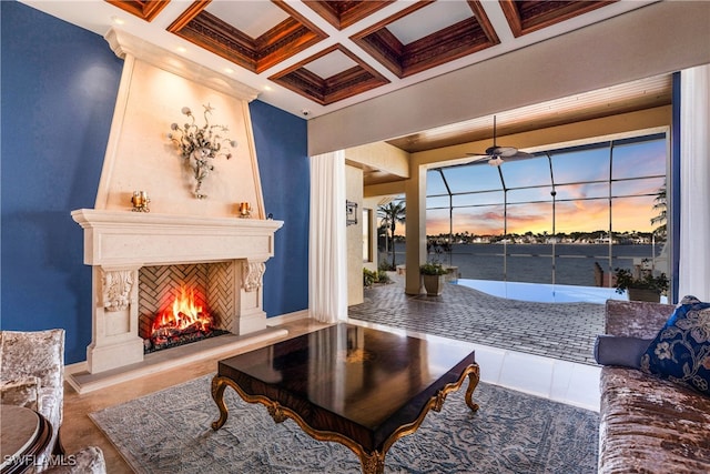 living room with beam ceiling, ceiling fan, coffered ceiling, crown molding, and a fireplace