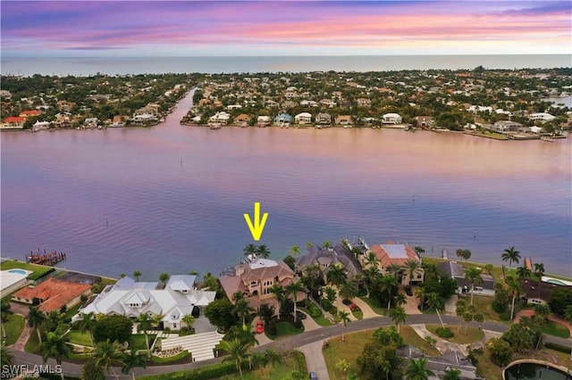 aerial view at dusk featuring a water view