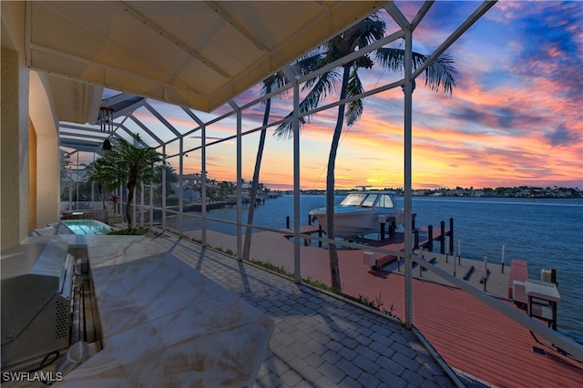 patio terrace at dusk featuring a lanai, a dock, and a water view