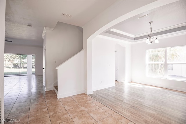 spare room featuring light wood-type flooring, ornamental molding, and an inviting chandelier