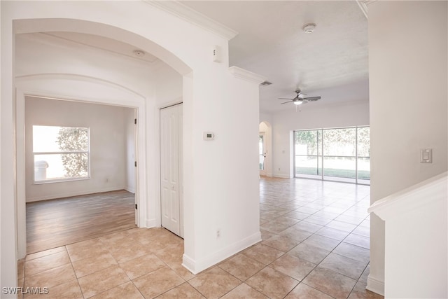 empty room featuring ceiling fan, light hardwood / wood-style floors, crown molding, and a wealth of natural light