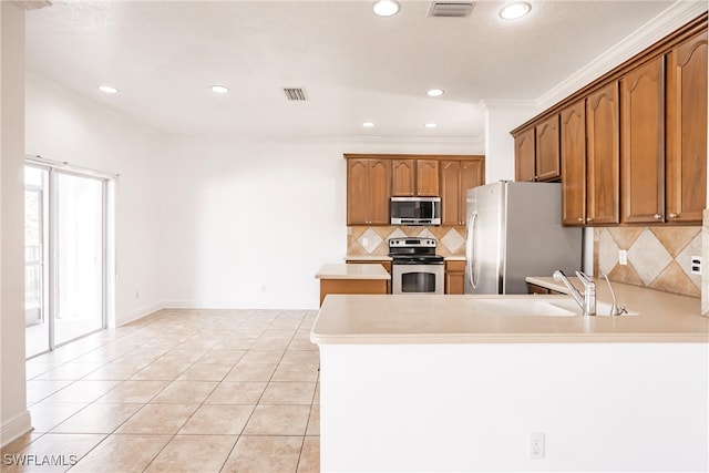 kitchen with sink, kitchen peninsula, appliances with stainless steel finishes, light tile patterned floors, and ornamental molding