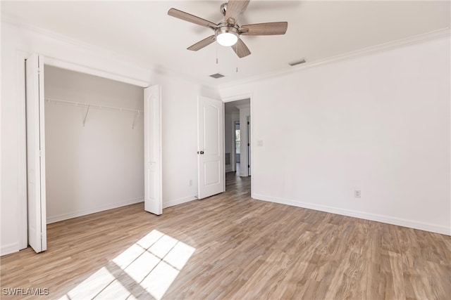 unfurnished bedroom with a closet, light hardwood / wood-style floors, ceiling fan, and crown molding