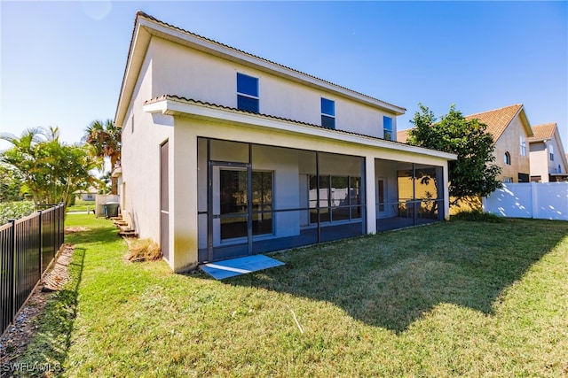 rear view of house featuring a sunroom and a yard