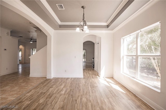 spare room with hardwood / wood-style floors, ceiling fan with notable chandelier, a raised ceiling, and ornamental molding