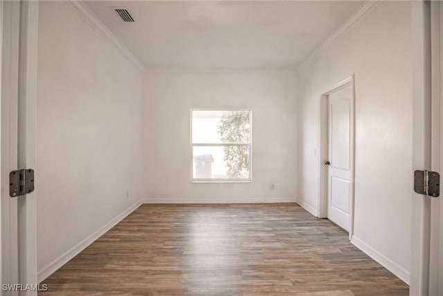 empty room featuring hardwood / wood-style flooring and ornamental molding