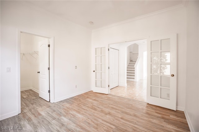 empty room featuring crown molding, french doors, and light hardwood / wood-style floors