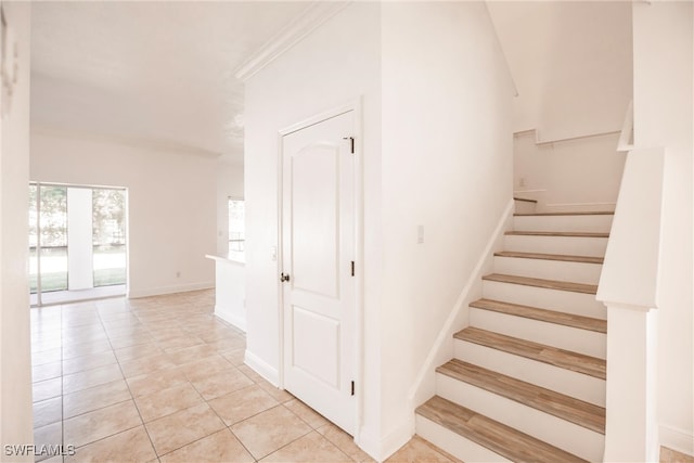 staircase with tile patterned floors and ornamental molding