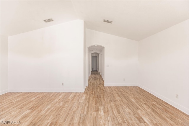 spare room featuring lofted ceiling and light wood-type flooring