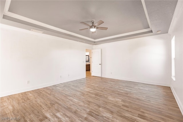 spare room with hardwood / wood-style flooring, ceiling fan, a raised ceiling, and crown molding