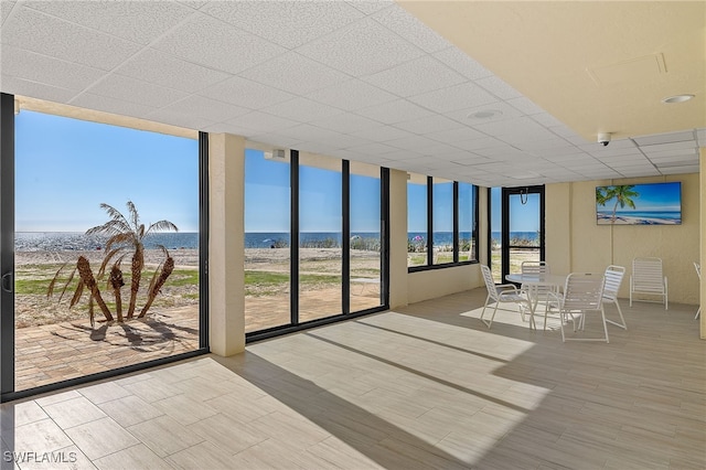 sunroom with a water view and a beach view