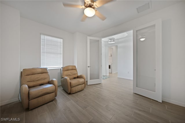 sitting room with ceiling fan, light wood-type flooring, and french doors