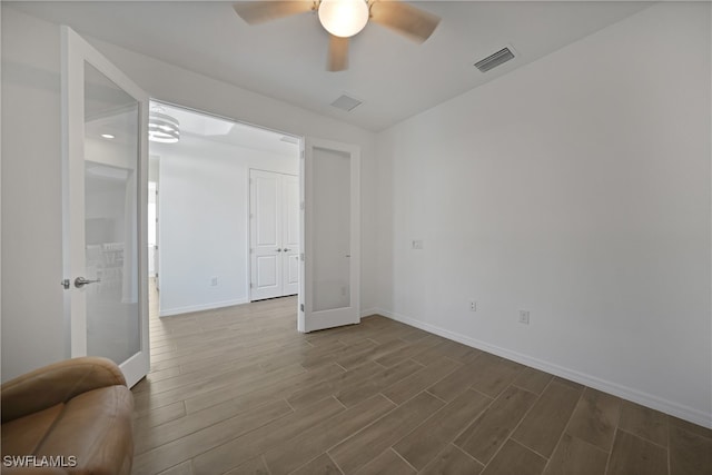 empty room featuring ceiling fan, french doors, and hardwood / wood-style floors