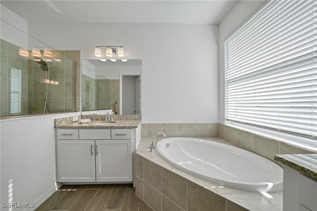 bathroom with hardwood / wood-style floors, vanity, plus walk in shower, and a wealth of natural light