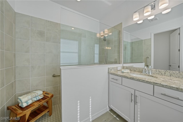 bathroom featuring a tile shower, tile patterned floors, and vanity