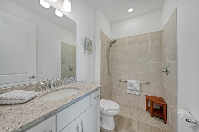 bathroom featuring tiled shower, vanity, and toilet