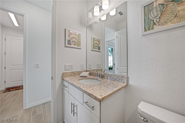 bathroom with vanity, wood-type flooring, and toilet