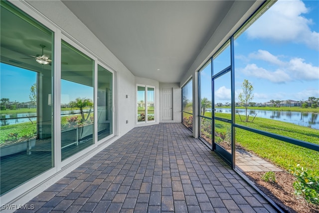 unfurnished sunroom with ceiling fan and a water view